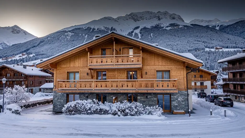 Résidence de location avec architecture alpine traditionnelle à la station de ski d'Arêches-Beaufort en hiver avec neige et montagnes.